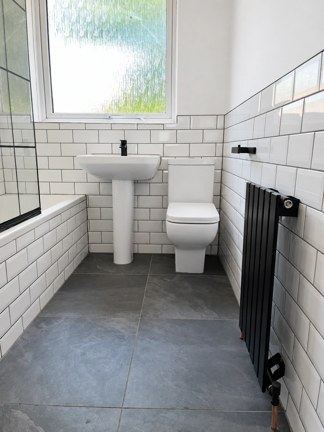 Completed grey bathroom with black radiator in Leeds