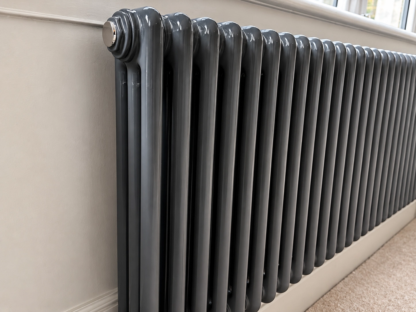 Dark column radiator beneath a window