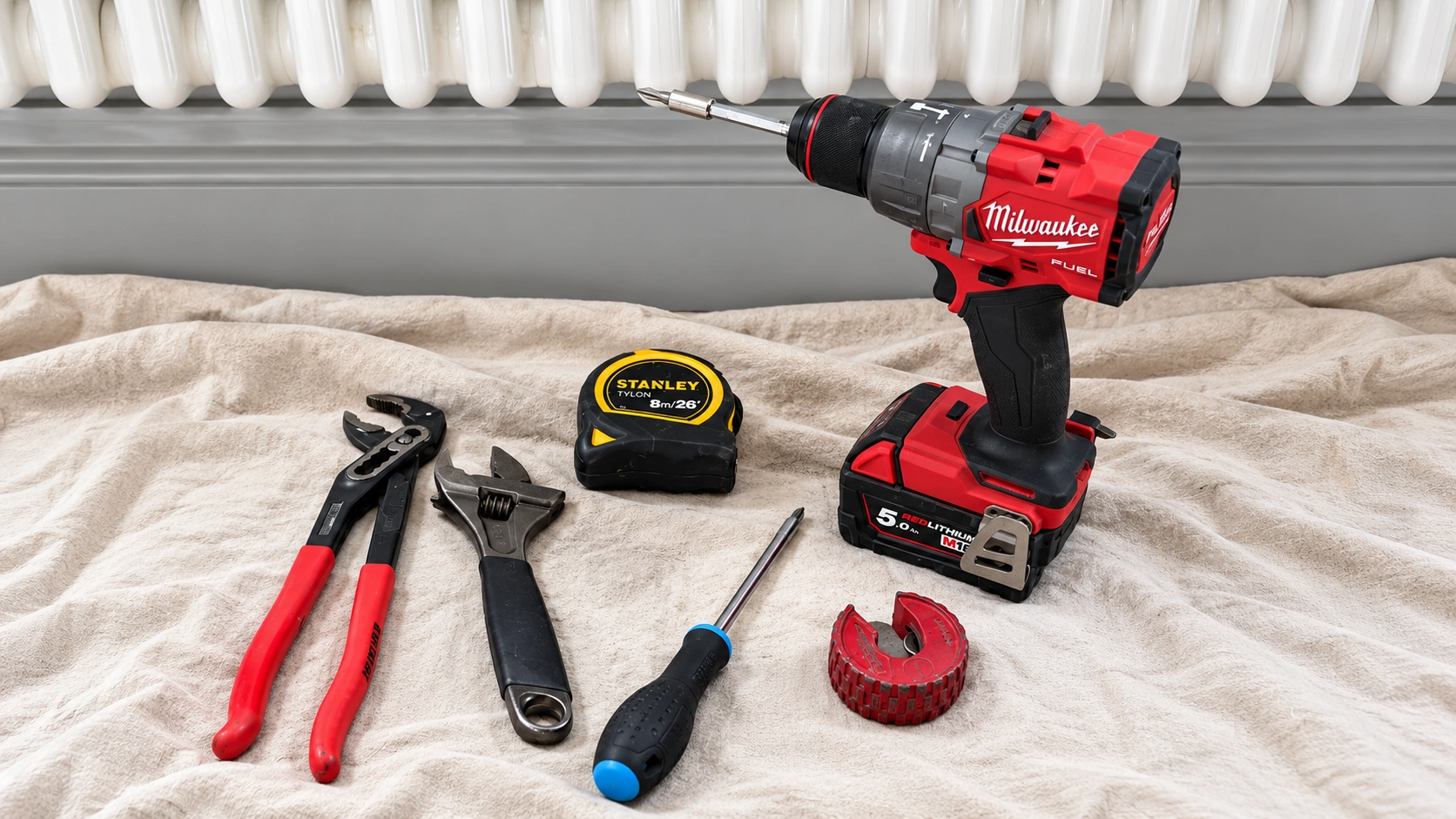 Plumbing tools on a protective cloth beside a radiator
