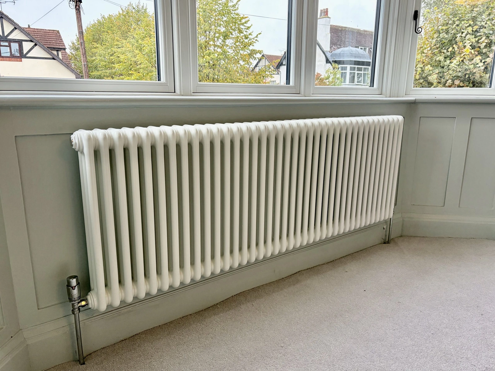 White column radiator installed beneath a bay window